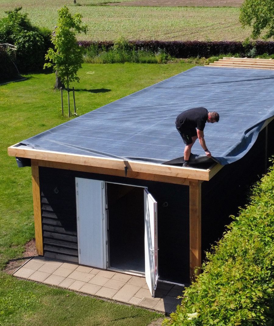 Dakdekker legt EPDM-folie op het platte dak van een tuinhuis